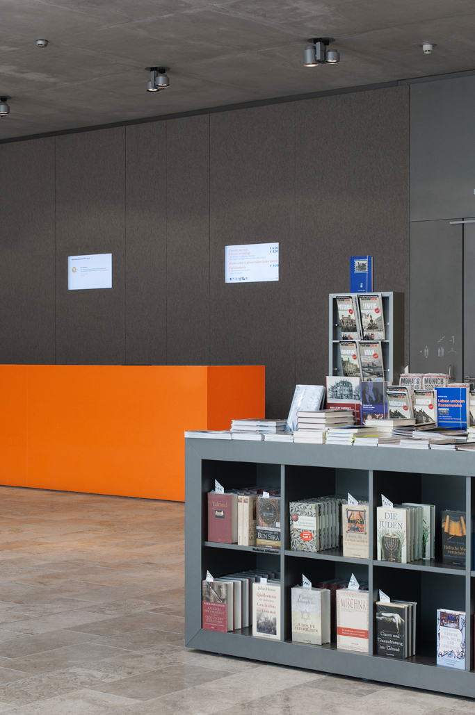 Büchertisch in MDF lackiert, Infotresen in Corian, Wandverkleidung mit Naturfilz